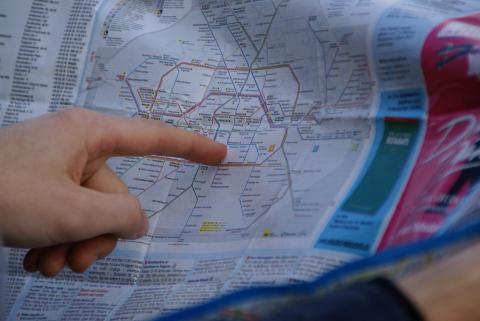 Ein Finger zeigt auf eine Karte. Jemand studiert das U-Bahn/S-Bahn/ÖV-Netz von Berlin