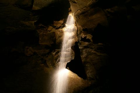 In einer dunklen Höhle gibt es einen Lichtblick. Ein Wasserfall fliesst stetig, prallt auf einen Stein und spritzt durch den Raum
